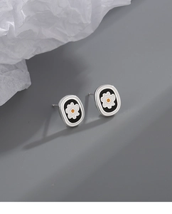 Macro side view of silver oval enamel flower studs with black base and white petals