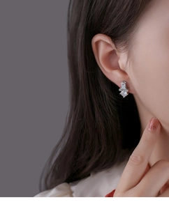 Close-up of heart-shaped zircon earring with Lucky engraved tag on male model ear