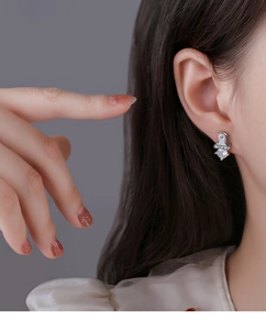 Detailed close-up of a silver earring with LUCKY engraving and a sparkling round crystal