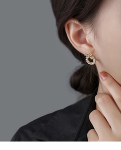 Close-up of elegant bow-shaped earring with white pearls and sparkling zircons