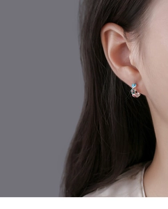 Macro side view of a woman wearing colorful enamel flower huggie earrings in 925 silver