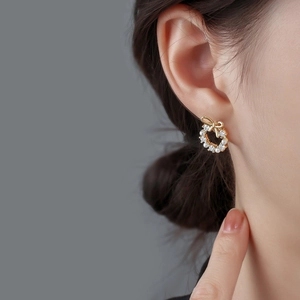 Elegant gold bow wreath earrings with small pearls and crystals worn by a model