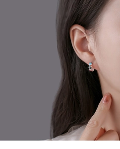 Macro shot of silver enamel flower hoop earrings worn on ear with colorful floral details