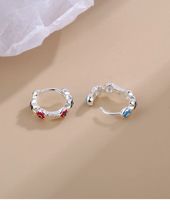 Detailed macro of S925 silver earrings featuring colorful enamel flowers on warm background