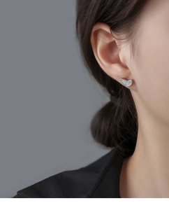 Detailed close-up of a silver butterfly wing earring with sparkling white zircons on ear