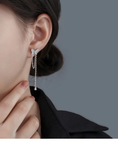 Close-up of asymmetric butterfly tassel earring with zircon inlay and teardrop crystal