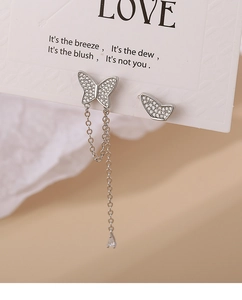 Detail of asymmetric butterfly tassel earrings with pavé zircons and drop pendant