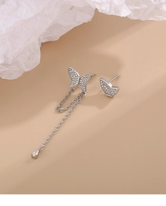 Macro shot of silver asymmetric butterfly earrings with crystal tassels and micro-pave zircons