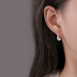 Minimalist silver water drop hoop earrings worn by a model in a close-up side view shot