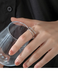Silver double-layer square geometric open ring on finger holding a glass cup