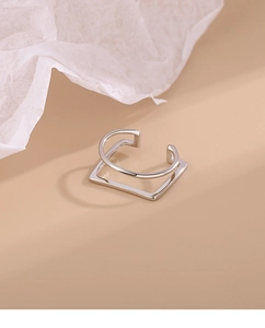 Detail of silver geometric square ear cuff with double layer design on neutral backdrop