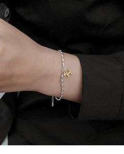 Close-up of silver beaded bracelet with golden H letter charm and sparkling zircon