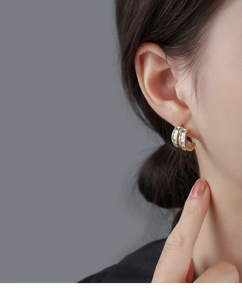 Close-up of elegant gold earrings with square-cut zircons worn on ear for women