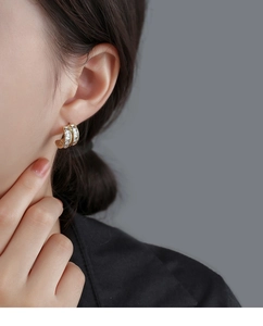 Close-up of gold C-shaped earrings with two rows of rectangular cut zircon stones