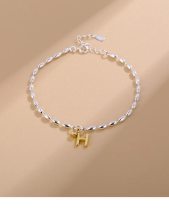Macro detail of S925 sterling silver beaded bracelet with H-letter charm and zircon
