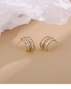 Detail view of gold-plated geometric earrings with double-row baguette zircon inlay