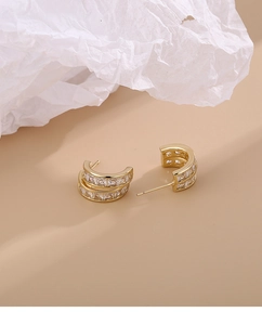 Detailed macro view of 18K gold-plated C-shaped earrings with double-row zircon setting