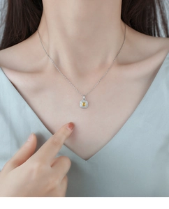 Close-up of yellow sugar cube zircon necklace with silver chain on model collarbone