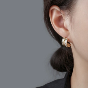 Elegant gold-plated C-shaped earrings with rectangular zircons on a female model