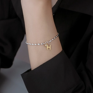 Elegant bead bracelet with golden H pendant and sparkling zircon charm on wrist