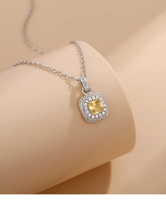 Detail of square yellow crystal pendant with halo diamonds on a silver chain