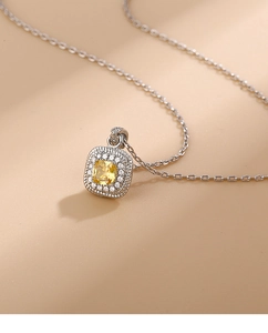Macro shot of yellow cushion cut crystal pendant with halo stones on silver chain