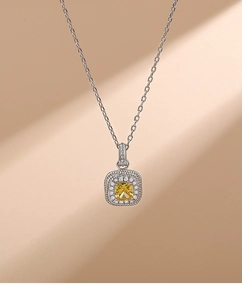 Detail of a luxury silver necklace with a yellow square crystal pendant and halo setting