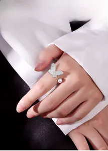 Detailopname van een elegante vlinderring met parel aan de hand in minimalistische stijl