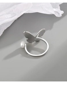 Detail van zilveren vlinderring met een glad vleugelontwerp en een wit parelaccentueertje