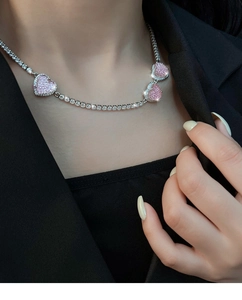 Nahaufnahme der funkelnden rosa Herzanhänger an einer silbernen Tennis-Halskette