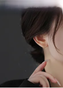 Detail of silver butterfly earring with pink heart zircon on model's ear