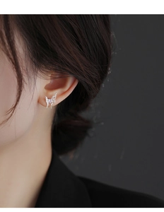 Detailed close-up of a silver liquid butterfly stud earring with a purple heart crystal