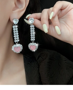 Nahaufnahme der rosa Herz-Ohrringe mit glitzernden Zirkonia-Quasten am Model