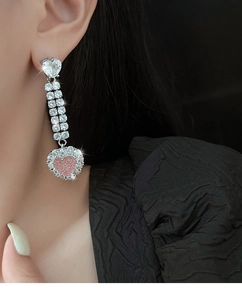 Details von rosa Herz-Quastenohrringen mit Silberbasis an einem weiblichen Model