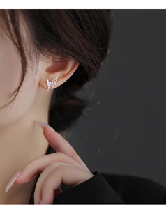 Detail of silver butterfly stud earring with hollow wings and pink heart-shaped stone