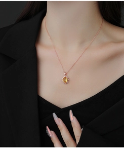 Détail du pendentif en cristal jaune ovale avec halo de diamants sur chaîne or rose