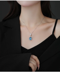 Détail d'un collier en argent avec pendentif saphir bleu ovale entouré de zircons blancs brillants