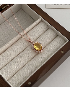 Gros plan d'un collier pendentif fleur en cristal jaune dans un coffret en bois