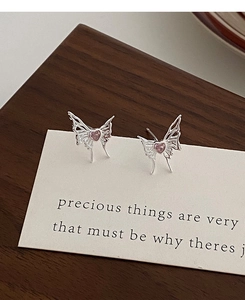 Detailed macro view of silver butterfly stud earrings with pink heart-shaped stones