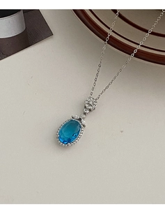 Détail d'un pendentif saphir bleu ovale avec halo de cristaux et fermoir fleur argenté