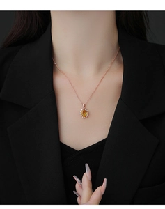 Gros plan d'un pendentif en cristal jaune en forme de fleur sur un collier en or rose