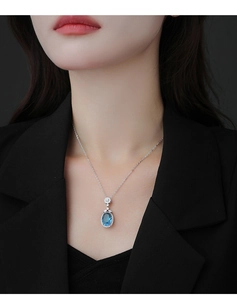 Gros plan d'un collier en argent avec pendentif saphir bleu porté par un mannequin femme