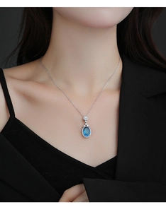 Gros plan du collier halo avec pendentif saphir bleu foncé sur une chaîne en argent