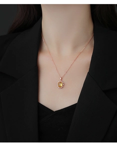 Gros plan d'un collier avec pendentif citrine jaune et chaîne en or rose sur un mannequin