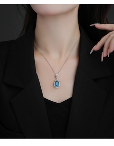Détail d'un collier en argent avec pendentif saphir ovale et halo de diamants sur modèle