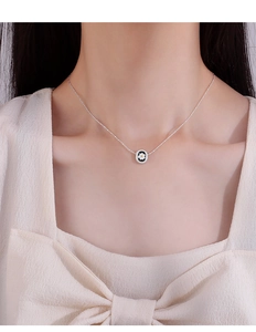 Close-up of a silver daisy flower pendant necklace worn on a female model neck