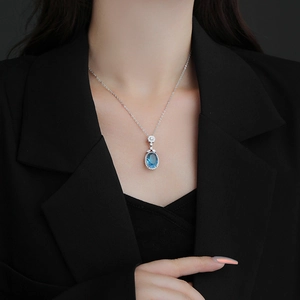 Élégant collier en argent avec pendentif saphir bleu ovale et diamants sur blazer noir