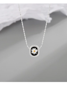 Macro detail of silver necklace with daisy flower pendant and black enamel finish