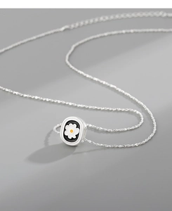 Macro detail of silver daisy pendant with black enamel frame on a delicate chain necklace