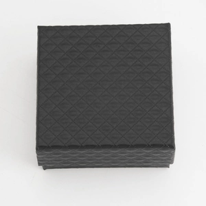Macro shot of a black square jewelry box with diamond pattern texture for rings and earrings